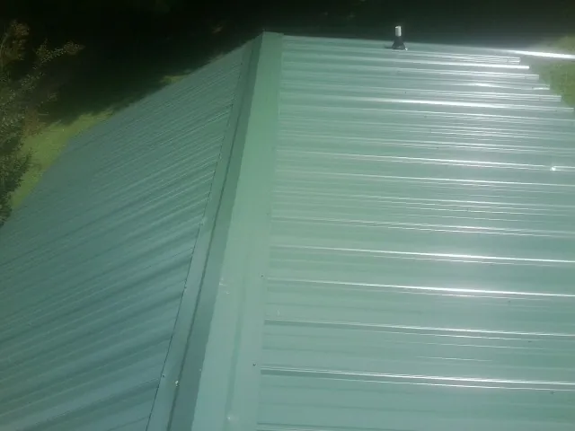 New green metal panels meeting at the ridge of a roof — Flat Roof Repair work by our crew in Waterford